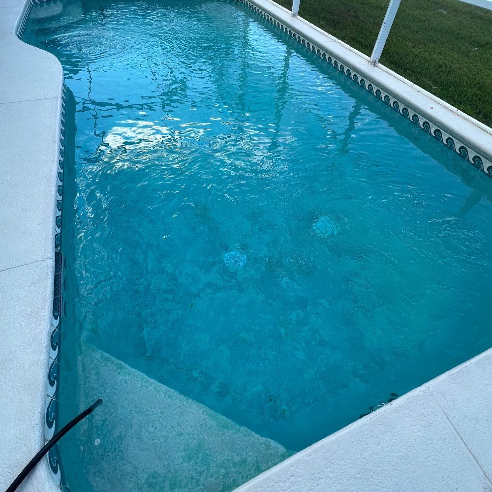 A blue swimming pool with a hose attached to it, after a finished maintenance